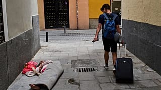 Un turista pasa junto a una mujer sin hogar en el centro de Madrid, España, el martes 3 de junio de 2025.