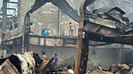 Des personnes cherchent des objets à récupérer dans les décombres d'un bâtiment incendié