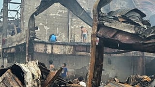 People search for items to salvage in the remains of a burnt building 