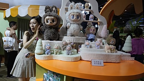 FILE. A visitor poses next to the Labubu collectible dolls displayed at the China International Fair for Trade in Services (CIFTIS) held in Beijing, China. 10 Sept. 2025.