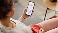 A woman looks at a period tracker app on her phone.
