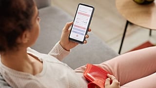 A woman looks at a period tracker app on her phone.