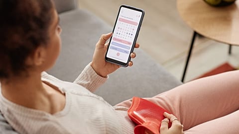 A woman looks at a period tracker app on her phone.