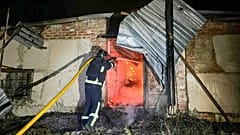 Ein Rettungshelfer löscht das Feuer eines durch einen russischen Angriff zerstörten Gebäudes in Charkiw.