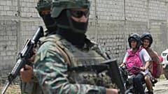 Los residentes pasan junto a miembros de la Fuerza Aérea en un puesto de control en el barrio La Delia de Durán, Ecuador, el viernes 12 de septiembre de 2025.