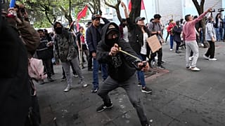 A protester slings a rock at police during protests