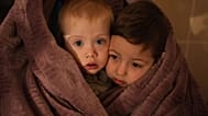 The children of medical workers warm themselves in a blanket as they wait for their relatives in a hospital in Mariupol, Ukraine, 4 March 2022