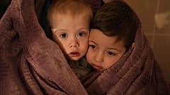Hijos de los trabajadores sanitarios se calientan con una manta mientras esperan a sus familiares en un hospital de Mariupol (Ucrania), el 4 de marzo de 2022.