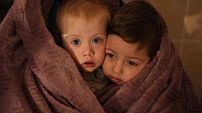 The children of medical workers warm themselves in a blanket as they wait for their relatives in a hospital in Mariupol, Ukraine, 4 March 2022