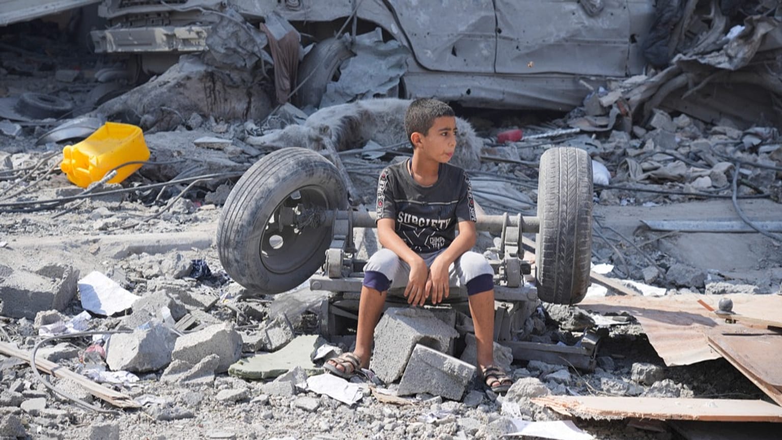 طفل فلسطيني يجلس فوق ركام مبناه الذي دُمّر في غارة إسرائيلية على مخيم النصيرات وسط قطاع غزة، يوم الاثنين 16 أكتوبر 2023.