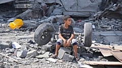 طفل فلسطيني يجلس فوق ركام مبناه الذي دُمّر في غارة إسرائيلية على مخيم النصيرات وسط قطاع غزة، يوم الاثنين 16 أكتوبر 2023.