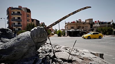 سيارة تسير بجانب تمثال مدمر في أعقاب الاشتباكات الطائفية التي وقعت الأسبوع الماضي في بلدة السويداء ذات الأغلبية الدرزية ، سوريا ، الجمعة 25 يوليو / تموز 2025.