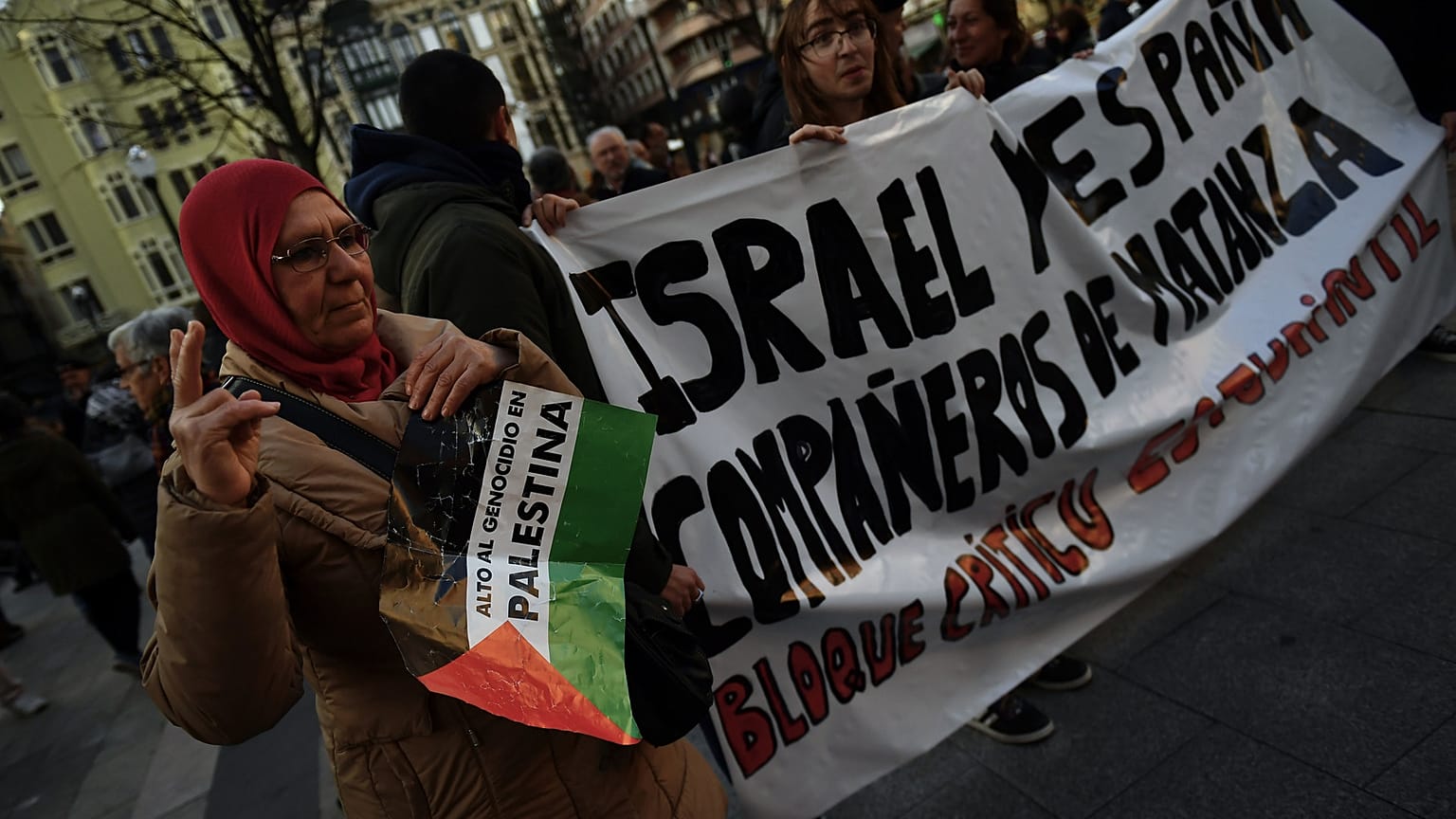 امرأة ترفع لافتة مكتوب عليها "أوقفوا إبادة فلسطين" وهي تشارك في مسيرة ضد إسرائيل