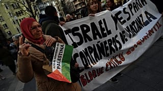 امرأة ترفع لافتة مكتوب عليها "أوقفوا إبادة فلسطين" وهي تشارك في مسيرة ضد إسرائيل