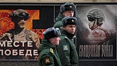 Eine Militärpatrouille geht an einer Straßenausstellung mit Militärplakaten mit dem Titel "Gemeinsam zum Sieg" vorbei, die der russischen Armee gewidmet ist, in St. Petersburg, Russland, Montag, 24. Februar 2025