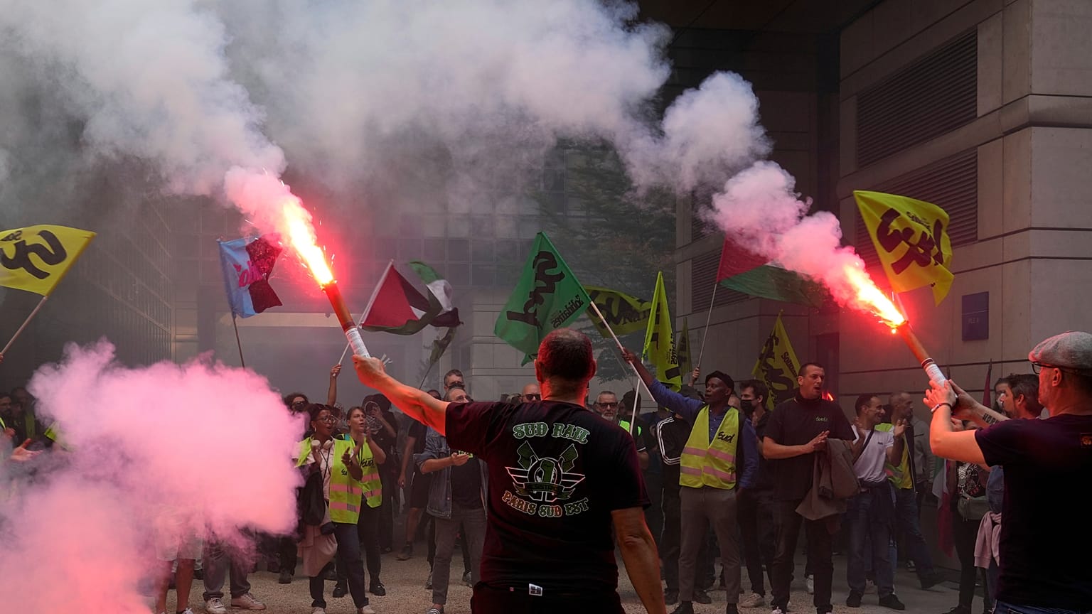 Striking rail workers wave flares into the Paris headquarters of the Economics Ministry during a protest called by major trade unions to oppose budget cuts, in Paris, 18 Septe