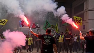 Striking rail workers wave flares into the Paris headquarters of the Economics Ministry during a protest called by major trade unions to oppose budget cuts, in Paris, 18 Septe