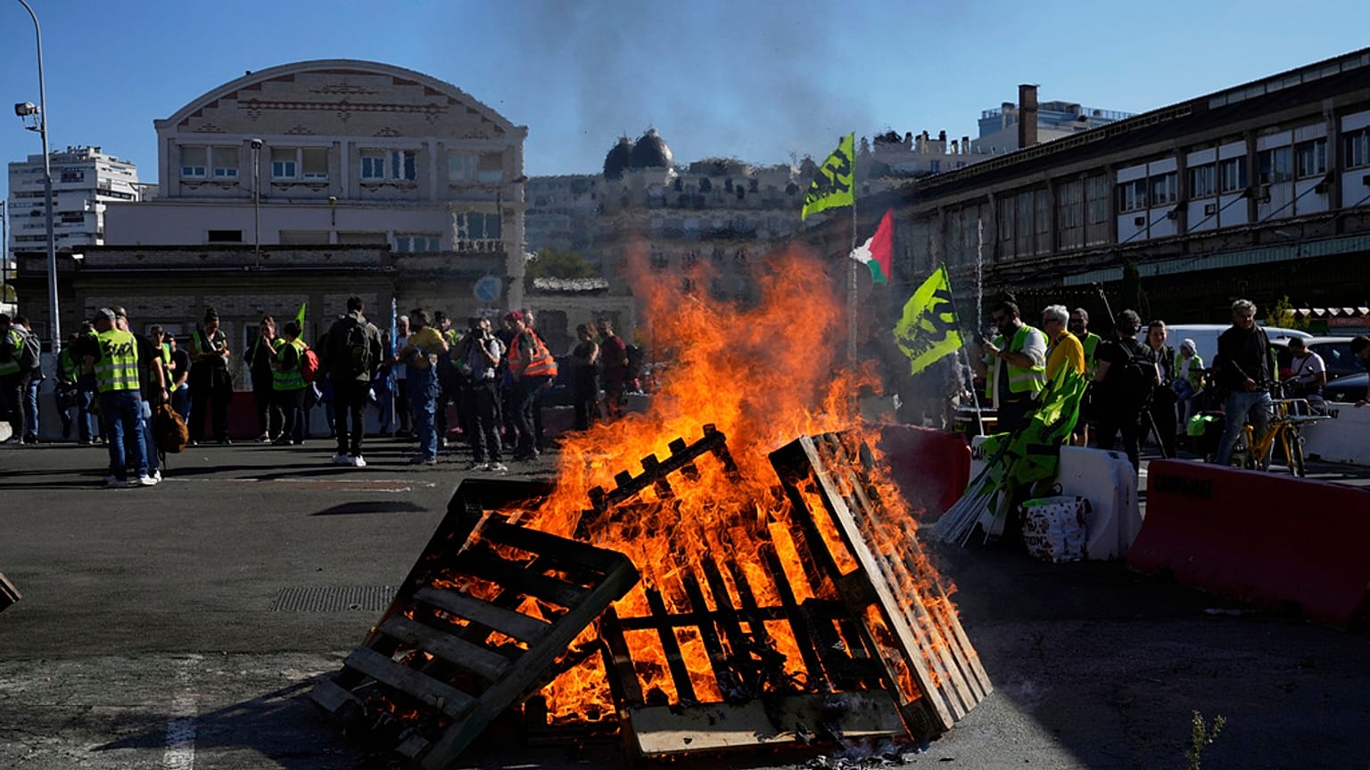 Des travailleurs se rassemblent à côté de palettes en bois en feu à la gare de Lyon, à Paris, le jeudi 18 septembre 2025.