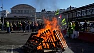 Des travailleurs se rassemblent à côté de palettes en bois en feu à la gare de Lyon, à Paris, le jeudi 18 septembre 2025.