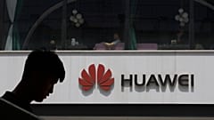 En esta foto de archivo del jueves 16 de mayo de 2019, un hombre se siluetea cerca del logotipo de Huawei en Pekín.