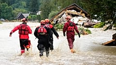 Os bombeiros caminham por uma estrada inundada em Jesenik, na República Checa, a 15 de setembro de 2024. 