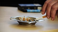 Una persona apaga su cigarrillo.