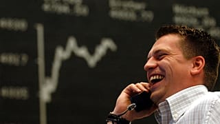 Batı Almanya'nın Frankfurt kentindeki borsada Alman Hisse Senedi Endeksi (DAX) panosunun önünde telefonla konuşan bir borsa yatırımcısı. 2005.