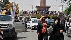 Kadınlar, ABD'nin çekilmesinin ve Taliban yönetiminin başlamasının dördüncü yıldönümü kutlamaları için Taliban savaşçıları ve destekçilerinden oluşan kalabalığın önünden yürüyor, 15 Ağustos 2025.