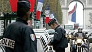 يقوم شرطي بفحص أوراق هوية سائق سيارة في جادة الشانزليزيه في باريس،