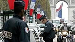 يقوم شرطي بفحص أوراق هوية سائق سيارة في جادة الشانزليزيه في باريس،