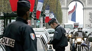 يقوم شرطي بفحص أوراق هوية سائق سيارة في جادة الشانزليزيه في باريس،