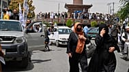 زنان برای برگزاری جشن چهارمین سالگرد خروج ایالات متحده و آغاز حکومت طالبان، ۱۵ اوت ۲۰۲۵، از میان جمعیت جنگجویان و حامیان طالبان عبور می کنند.