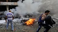 رجل يركض أمام سيارة محترقة في موقع الانفجارين بالقرب من السفارة الإيرانية في بيروت، لبنان. 19 نوفمبر/ تشرين الثاني 2013.