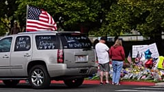 Auf einem Lastwagen weht eine US-Flagge, auf deren Scheiben Botschaften zum Gedenken an Charlie Kirk geschrieben sind. Die Menschen versammeln sich zu einer Gedenkfeier an der Utah Valley University in Orem, 13. September 2025.