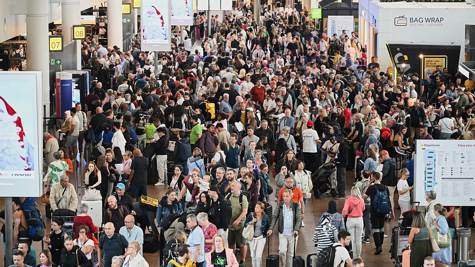 People walk by a departures board after a cyber attack caused delays at Brussels International Airport in Zaventem, Belgium, Saturday, Sept. 20, 2025.