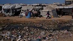Une Palestinienne passe devant des eaux usées à ciel ouvert dans une zone d'un camp de tentes de fortune pour personnes déplacées à Zawaida, dans le centre de la bande de Gaza