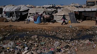 Une Palestinienne passe devant des eaux usées à ciel ouvert dans une zone d'un camp de tentes de fortune pour personnes déplacées à Zawaida, dans le centre de la bande de Gaza