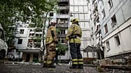 Rescue workers stand in front of a residential building damaged after a Russian strike on Dnipro, Ukraine, Saturday, Sept. 20, 2025