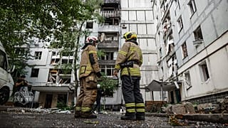 Rescue workers stand in front of a residential building damaged after a Russian strike on Dnipro, Ukraine, Saturday, Sept. 20, 2025