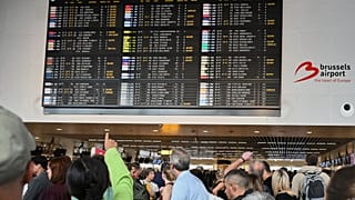 An airport employee points at a departure board after a cyber attack caused delays at Brussels International Airport in Zaventem, Belgium, Saturday, Sept. 20, 2025.