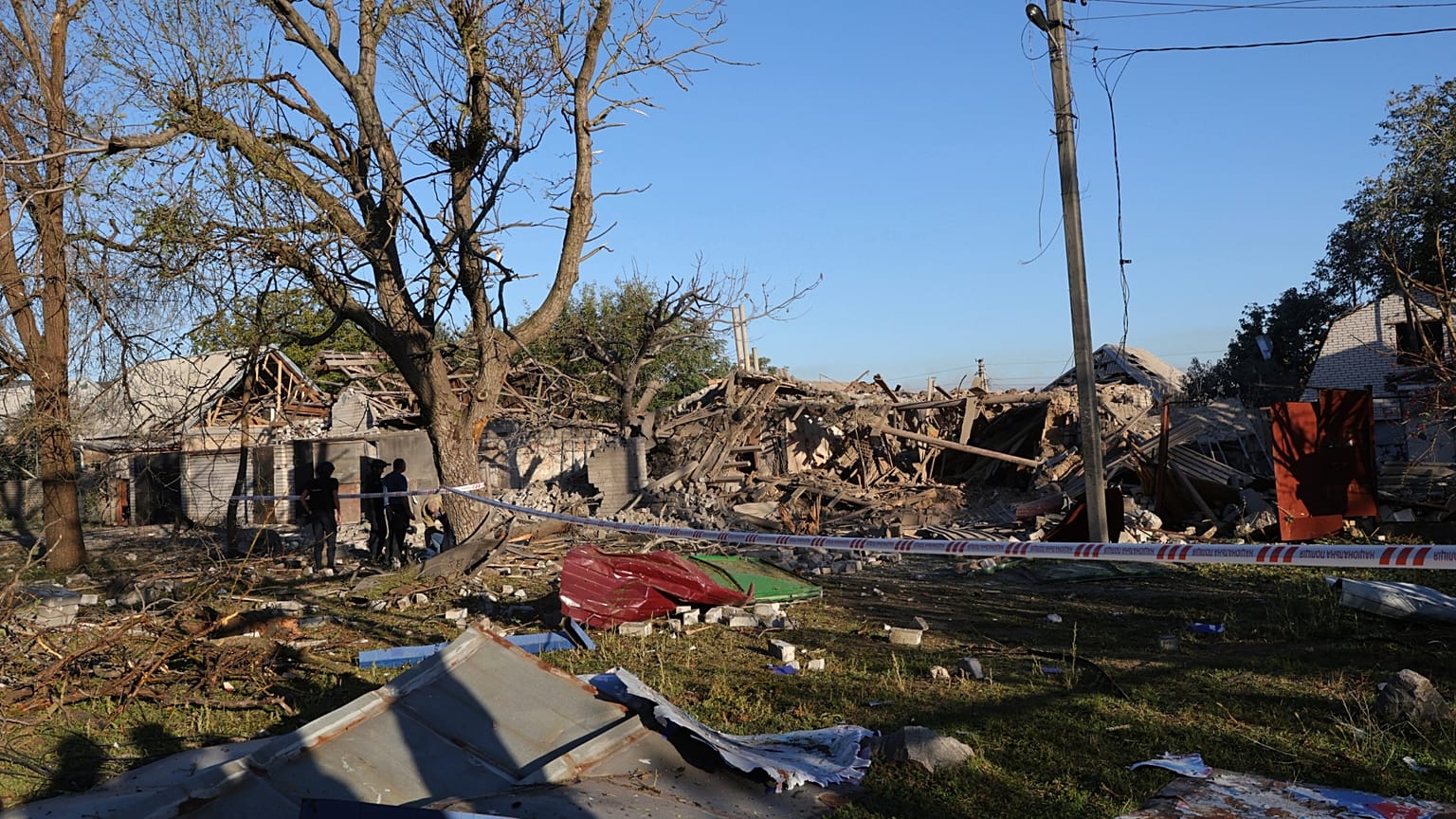 Persone in piedi vicino a un edificio distrutto durante un attacco russo a Zaporizhzhia