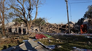 People stand near a building destroyed during a Russian strike in Zaporizhzhia