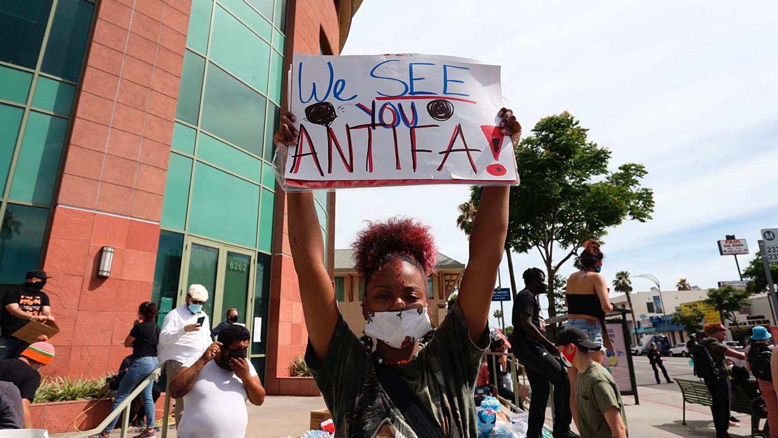 A woman holds a sign addressing ANTIFA at a protest in Los Angeles on Monday, June 1, 2020, over the death of George Floyd, who died  in Minneapolis.