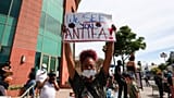 Una donna tiene un cartello rivolto agli ANTIFA durante una protesta a Los Angeles, lunedì 1 giugno 2020, per la morte di George Floyd, deceduto a Minneapolis.
