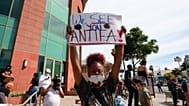 A woman holds a sign addressing ANTIFA at a protest in Los Angeles on Monday, June 1, 2020, over the death of George Floyd, who died  in Minneapolis.