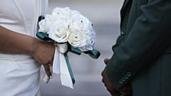 يقف زوجان مواجهةً لبعضهما البعض خلال حفل زفاف جماعي بمناسبة عيد الحب على درجات محكمة مقاطعة ديد في ميامي.