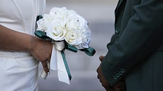 يقف زوجان مواجهةً لبعضهما البعض خلال حفل زفاف جماعي بمناسبة عيد الحب على درجات محكمة مقاطعة ديد في ميامي.