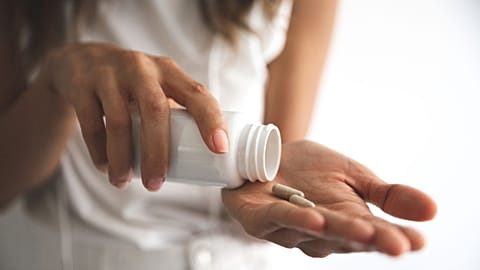 A woman takes a pill.