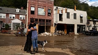 Resident Anne Schneider, right, hugs her friend, Eddy Sampson, as they survey damage caused by Hurricane Helene on Oct. 1, 2024.