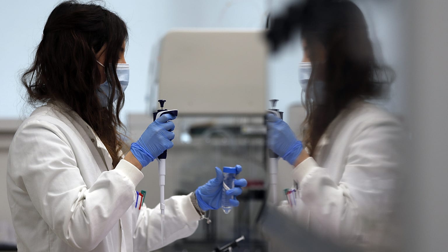 مساعدة مختبر تستخدم الماصّة لتحضير RNA لفيروس كورونا من أجل التسلسل الجيني في معهد ويلكوم سانجر الذي تديره أبحاث الجينوم في كامبريدج